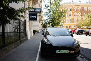 Varşova, Polonya - 02 Temmuz 2025: Gündüz vakti Polonya 'nın Varşova kentindeki bir caddeye park edilmiş modern siyah Tesla Model Y arabası