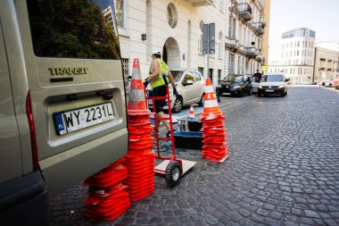 Varşova, Polonya - 2 Temmuz 2025: Bir işçi Varşova caddesindeki trafik konilerini taşımak için el kamyonu kullanıyor.