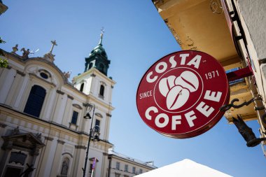 Varşova, Polonya - 2 Temmuz 2025: Red Costa Kahve tabelası güneşli Varşova 'nın tarihi mimarisine belirgin bir şekilde karşıydı