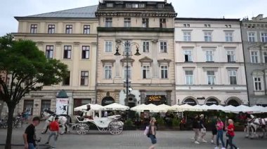 Krakow, Polonya - 08 Temmuz 2025: Tarihi Rynek Parıltısı 'nın tadını çıkaran turist ve yerlilerin arabaları ve kafeleriyle dolu canlı sahneleri.