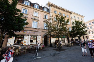 Varşova, Polonya - 02 Temmuz 2025: Varşova 'da güneşli bir günde klasik binaların önündeki açık kafeler ve ağaçlar