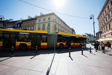 Varşova, Polonya - 02 Temmuz 2025: Günışığı altında Varşova şehir merkezinde modern sarı elektrikli otobüs