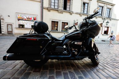 Varşova, Polonya - 02 Temmuz 2025: Parlak siyah bir Harley-Davidson Road Glide motosikleti Polonya 'nın Varşova kentinde tarihi bir mimarinin yakınına park edilmiştir..