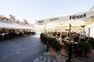 Varşova, Polonya - 2 Temmuz 2025: Varşova 'nın tarihi bölgesinde şemsiyeler ve kaldırımtaşı caddelerin yer aldığı Büyüleyici Bazyliszek sokak kafesi