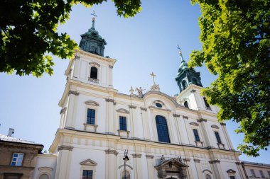 Güneşli bir günde yemyeşil yapraklarla çerçevelenmiş Kutsal Haç Kilisesi 'nin tarihi mimarisi. Varşova, Polonya. 