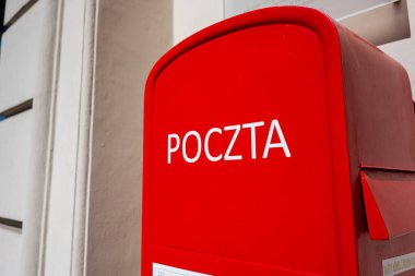 Güneşli bir günde açık havada 'Poczta' yazan kırmızı bir Polonyalı posta kutusu