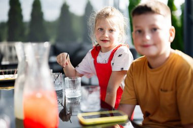 İki çocuk güneşli bir günde açık bir masada yemek yiyor..