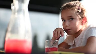 Güzel genç bir kız lezzetli bir kırmızı içki yudumluyor, kaygısız ve keyifli bir anın tadını çıkarıyor..