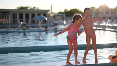 Neşeli genç kızlar havuzda eğlenceli bir yaz günü kahkahalarını ve sıcak bir kucaklaşmayı paylaşırlar..