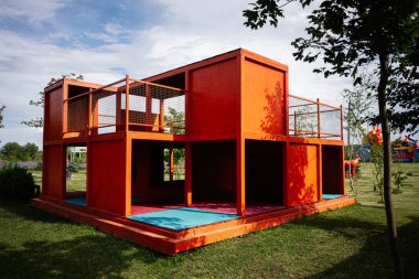 Çimenli tarlalarla çevrili bir parkta turuncu bir oyun alanı..