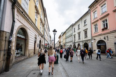 Krakow, Polonya - 08 Temmuz 2025: Polonya 'nın Krakow kentindeki renkli binaların önünden geçen turistlerle dolu kalabalık şehir caddesi