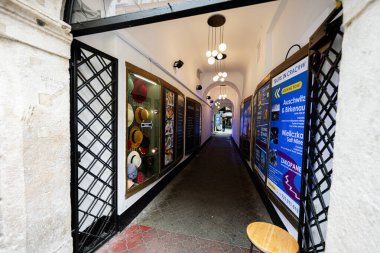 Krakow, Polonya - 08 Temmuz 2025: Tur reklamları ve tavan lambalarıyla aydınlatılmış şapkaların yer aldığı bir Krakow geçidi.