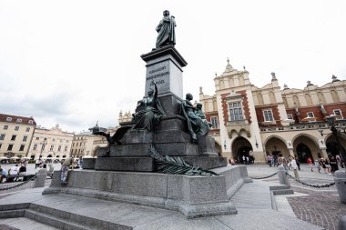 Krakow, Polonya - 08 Temmuz 2025: Adam Mickiewicz heykeli çevresindeki tarihi binalarla Krakow Ana Meydanı 'nda yer almaktadır