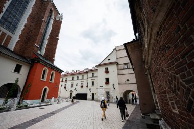 Krakow, Polonya - 08 Temmuz 2025: Polonya 'nın Krakow kentinde tarihi binalar ve yürüyen ziyaretçilerin yer aldığı büyüleyici bir cadde