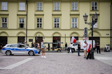 Krakow, Polonya - 08 Temmuz 2025: Krakow 'da insanlar, araçlar ve polis varlığının yer aldığı canlı bir sokak manzarası.