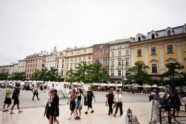 Krakow, Polonya - 08 Temmuz 2025: Krakow, Polonya - 08 Temmuz 2025: Polonya 'daki tarihi binalarla dolu kasaba meydanında yürüyen insanlar