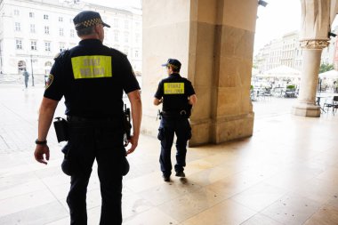 Krakow, Polonya - 8 Temmuz 2025: Polonya 'nın Krakow kentindeki tarihi binaların altında yürüyen polis memurları