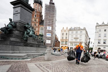 Krakow, Polonya - 08 Temmuz 2025: Meşgul bir Krakow meydanında ünlü çöp torbaları taşıyan sokak temizleyicisi