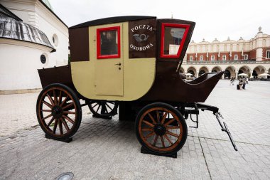 Krakow, Polonya - 08 Temmuz 2025: Tarihi binalarla çevrili Krakow şehir meydanında antika posta arabası sergilendi.