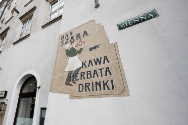 Krakow, Polonya - 8 Temmuz 2025: Krakow, Polonya 'daki bir binanın duvar sanatı, klasik bir Szara bar temasını gözler önüne seriyor.