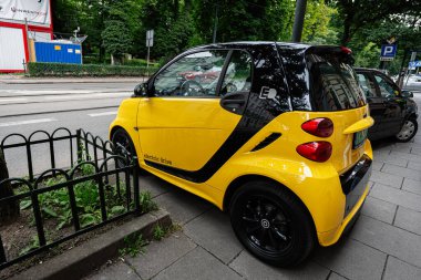 Krakow, Polonya - 08 Temmuz 2025: Krakow 'da şehir yeşiliyle çevrili bir caddede sıkışık sarı Smart ForTwo elektrikli araba