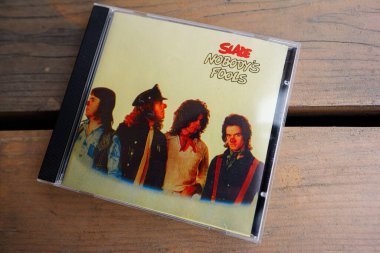Lymshory, Ukrayna - 31 Temmuz 2025: Slade Nobody 's Fools' un yer aldığı CD albüm kapağı, rustik ahşap bir masaya yerleştirildi
