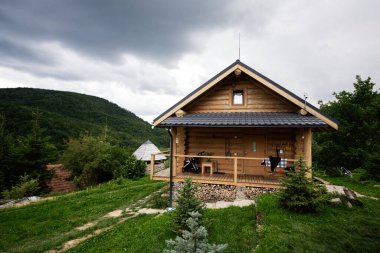 Dağların ortasında yeşil bir kulübe ve bulutlu bir atmosfer..