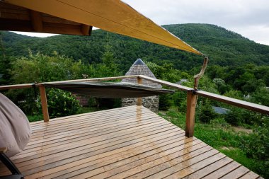 Güzel dağ ve orman manzaralı bir hamağın olduğu huzurlu ahşap bir güverte.