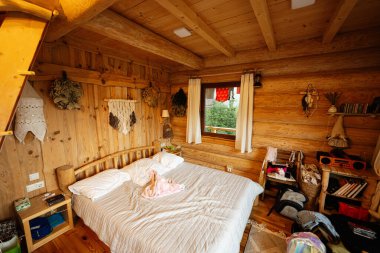 Sıcak dekor elementleri ve yumuşak yatağı olan rahat ahşap yatak odası.