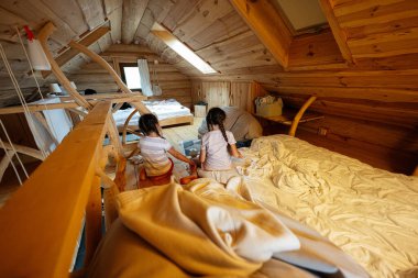 İki çocuk, sakin bir ahşap tavan arasında oyun oynayıp rahatlıyor.