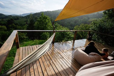 Açık hava verandası, hamak, armut çuvalı ve güneşli bulutların altında büyüleyici yeşillik.