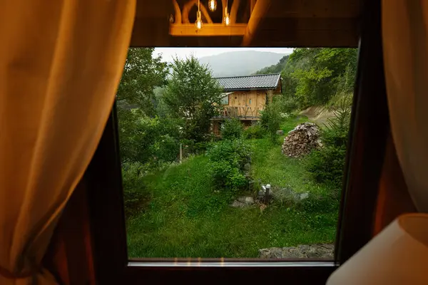 Yeşil ormandaki sakin ahşap kulübe, pencereden güzel görünüyor..