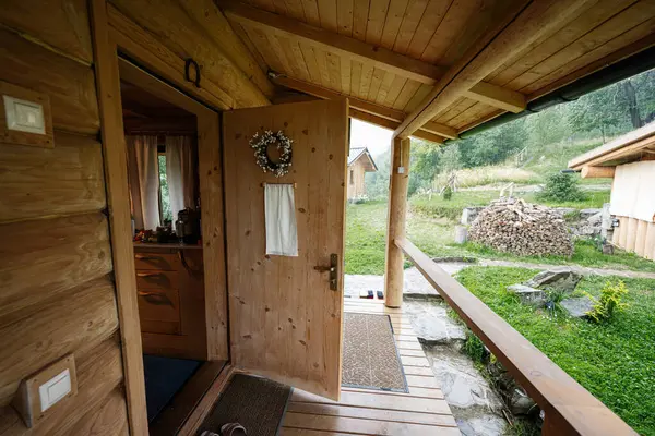 Tabiat manzaralı ve yakacak odunları olan ahşap bir kulübeye huzurlu bir veranda girişi..