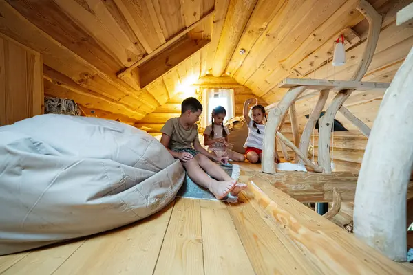 Çocuklar rahat, ahşap bir çatı katında oyun oynuyorlar.