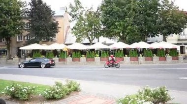 Lancut, Polonya - 22 Ağustos 2025: Arabalar ve motosiklet, Polonya 'nın Lancut kentindeki sakin bir kasaba caddesinde, açık kafeleri olan bir seyahat.