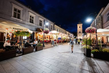Rzeszow, Polonya - 22 Ağustos 2025: Rzeszow, Polonya 'daki yemek mekanları ve yayalarla samimi bir akşam manzarası