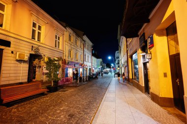 Rzeszow, Polonya - 22 Ağustos 2025: Polonya 'nın Rzeszow kentinde aydınlatılmış dükkanları olan parke taşlı bir caddenin büyüleyici gece manzarası.
