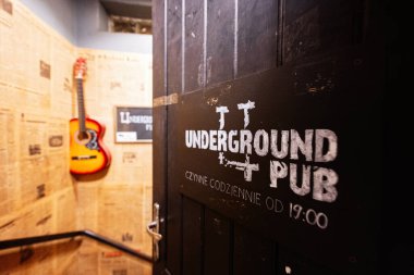 Rzeszow, Polonya - 22 Ağustos 2025: Polonya, Rzeszow 'da temalı bir iç mekanda bar tabelası ve gitarı olan ahşap kapı
