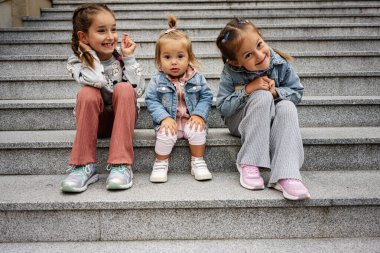 Przemysl, Polonya 'da merdivenlerde birlikte oturan üç mutlu çocuk..