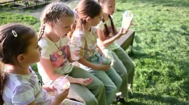 Genç kızlar parktaki bankta dinlenirken soğuk içeceklerle kendilerini tazelerler..