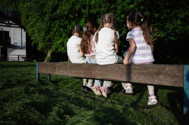 Aydınlık ve güneşli bir günde bir grup çocuk birlikte dışarıda eğleniyor.