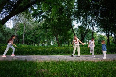 Çocuklar ağaçlar ve yeşilliklerle çevrili eğlenceli bir açık hava aktivitesinin tadını çıkarıyorlar..