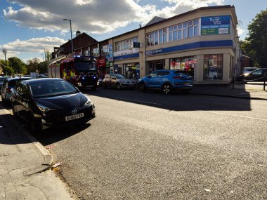 Manchester, İngiltere - 23 Eylül 2025: Manchester caddesi güneşli bir günde araçlar, itfaiye aracı ve bir Tesco Express mağazası ile dolu.