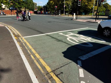 Manchester, İngiltere - 23 Eylül 2025: Manchester kavşağında güneşli bir günde yayalar, bir puset ve bisiklet yolunu gösteren şehir manzarası.