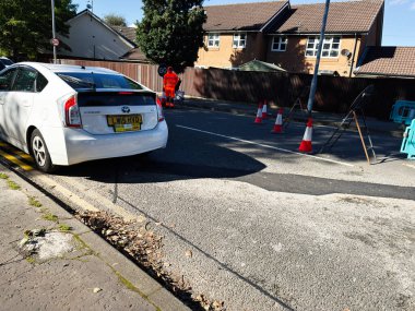 Manchester, İngiltere - 23 Eylül 2025: Manchester 'da bir turuncu güvenlik çalışanı, koniler ve park halindeki beyaz bir arabayı gösteren yerleşim yeri.