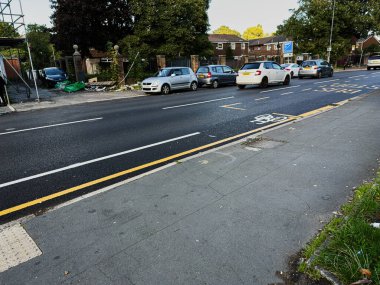 Manchester, İngiltere - 23 Eylül 2025: Manchester 'da park halindeki araçlar, bir bisiklet şeridi ve görünür bir konut arkaplanı.