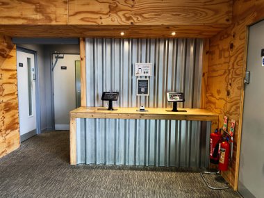 Salford, İngiltere - 23 Eylül 2025: Salford 'da tabletler, ahşap sayaç ve güvenlik ekipmanlarıyla modern endüstriyel resepsiyon alanı.