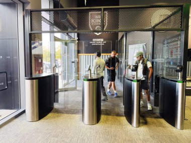 Salford, İngiltere - 23 Eylül 2025: İnsanlar güvenli erişim ve giriş için şirket lobisindeki modern turnikeli kullanıyorlar.