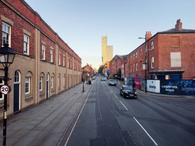 Manchester, İngiltere - 23 Eylül 2025: Manchester 'daki Urban Liverpool caddesi kırmızı tuğlalı sıra, uzak siluet ve hafif trafik.