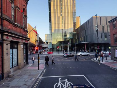 Manchester, İngiltere - 23 Eylül 2025: Cam bina, tuğla mimari, yayalar ve araçlarla dolu Manchester kavşağı.